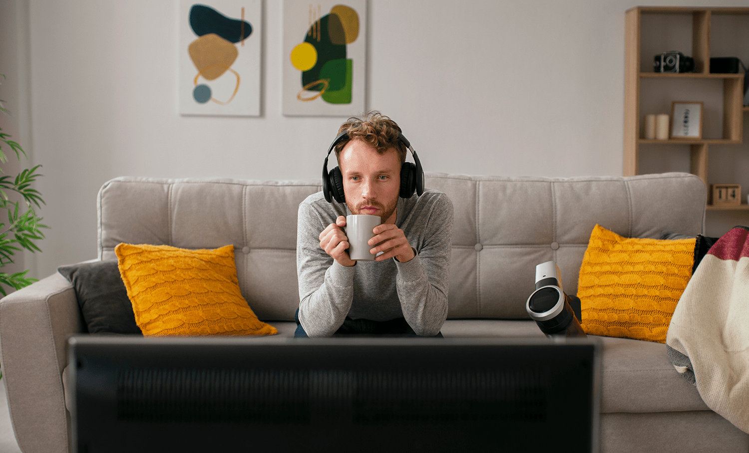 Homem com fones e caneca, focado na tela. Ilustra consumo de mídia e atenção em campanhas digitais.