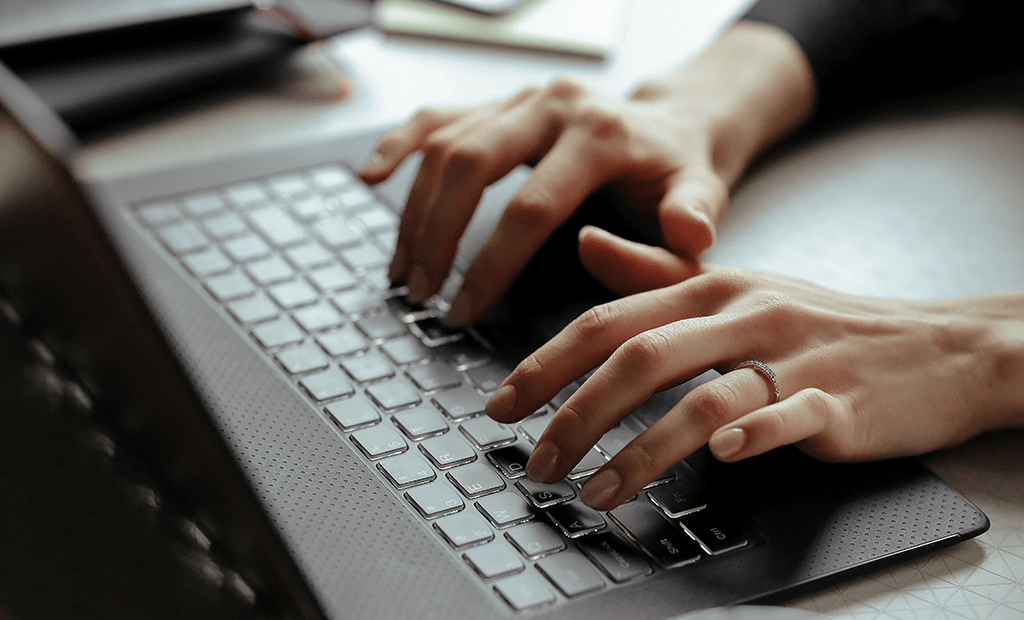 Mãos digitando em um teclado de laptop, ilustrando a interação com tecnologia e o tema da acessibilidade digital nas diretrizes WCAG 3.0.