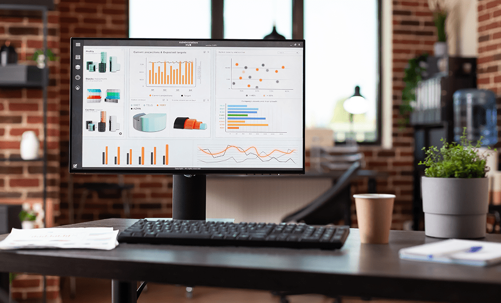 Monitor exibindo painel com gráficos e métricas em ambiente de escritório, representando análise de dados e monitoramento ativo.