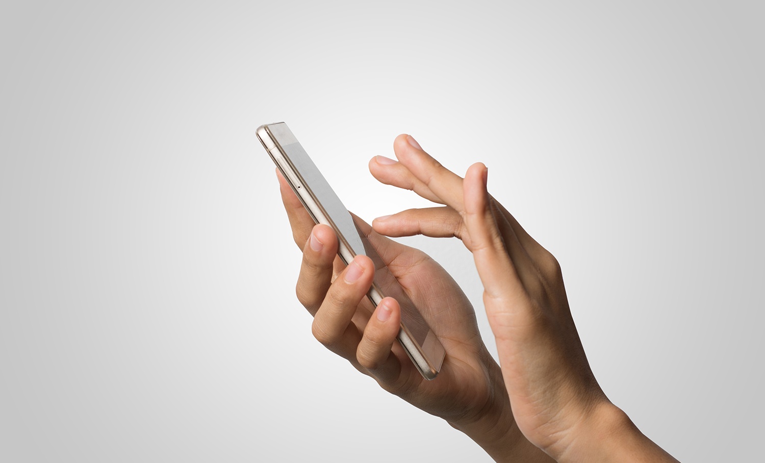 Mãos segurando um smartphone dourado contra fundo cinza claro, com o dedo indicador da mão direita prestes a tocar a tela.