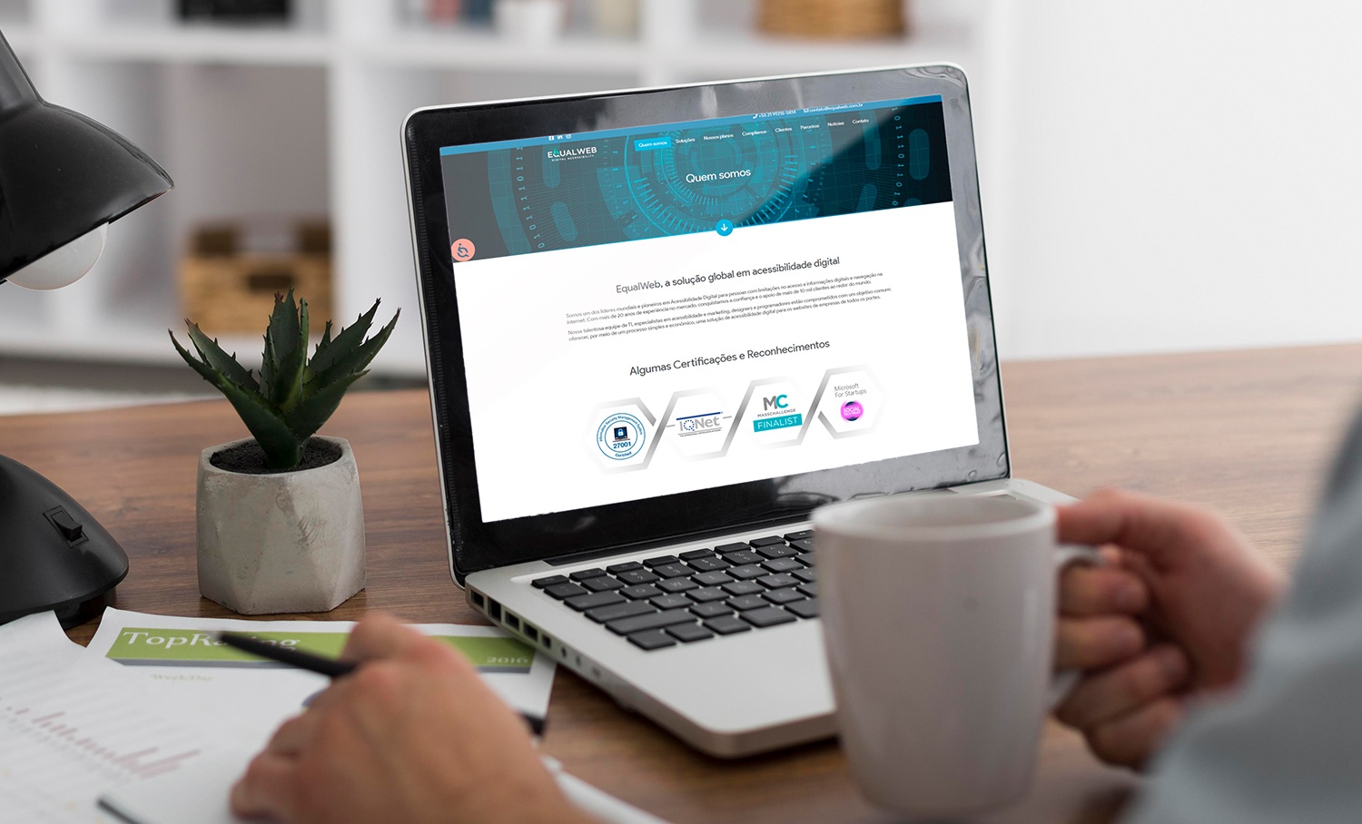 Laptop exibe site da EqualWeb sobre acessibilidade digital e certificações, ilustrando a integração do tema com ESG em ambiente de trabalho.