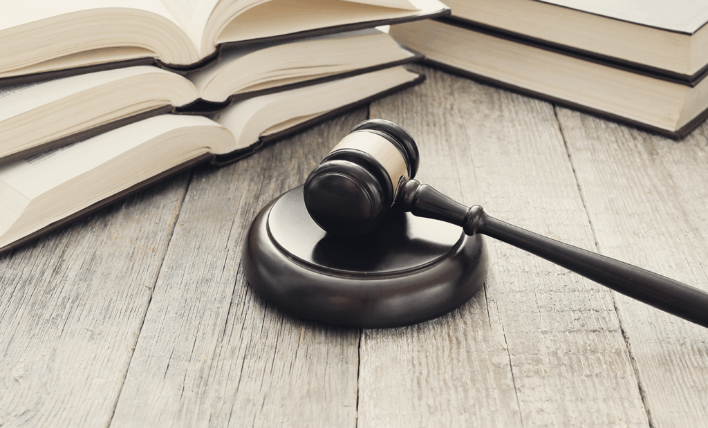acessível. Imagem de um martelo da justiça em cima de uma mesa e ao lado de alguns livros abertos. 