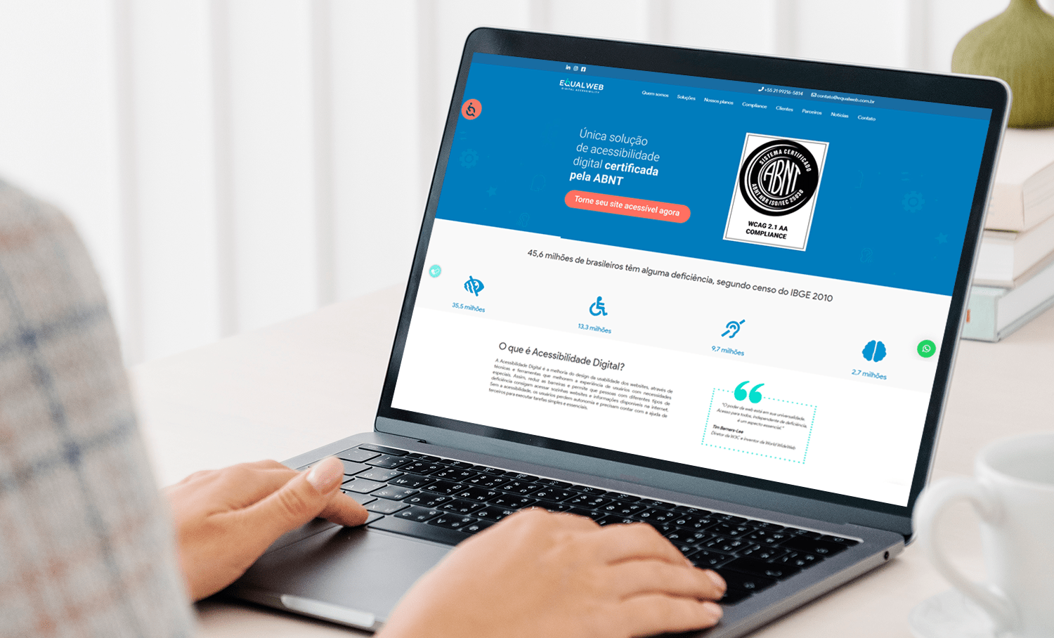Laptop exibindo site da EqualWeb com certificação ABNT e dados sobre acessibilidade digital, mostrando ícones e estatísticas do IBGE.