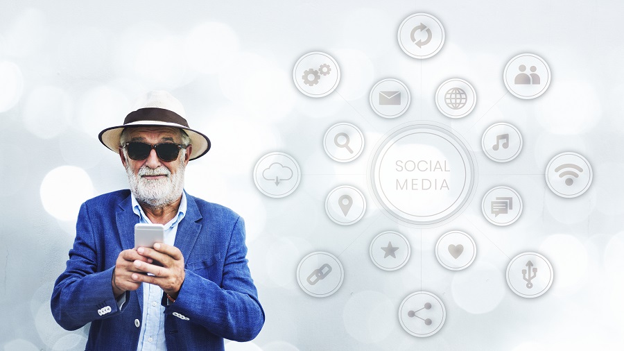 Idoso com óculos usa smartphone perto de ícones "Social Media", ilustrando acessibilidade e inclusão nas redes sociais.