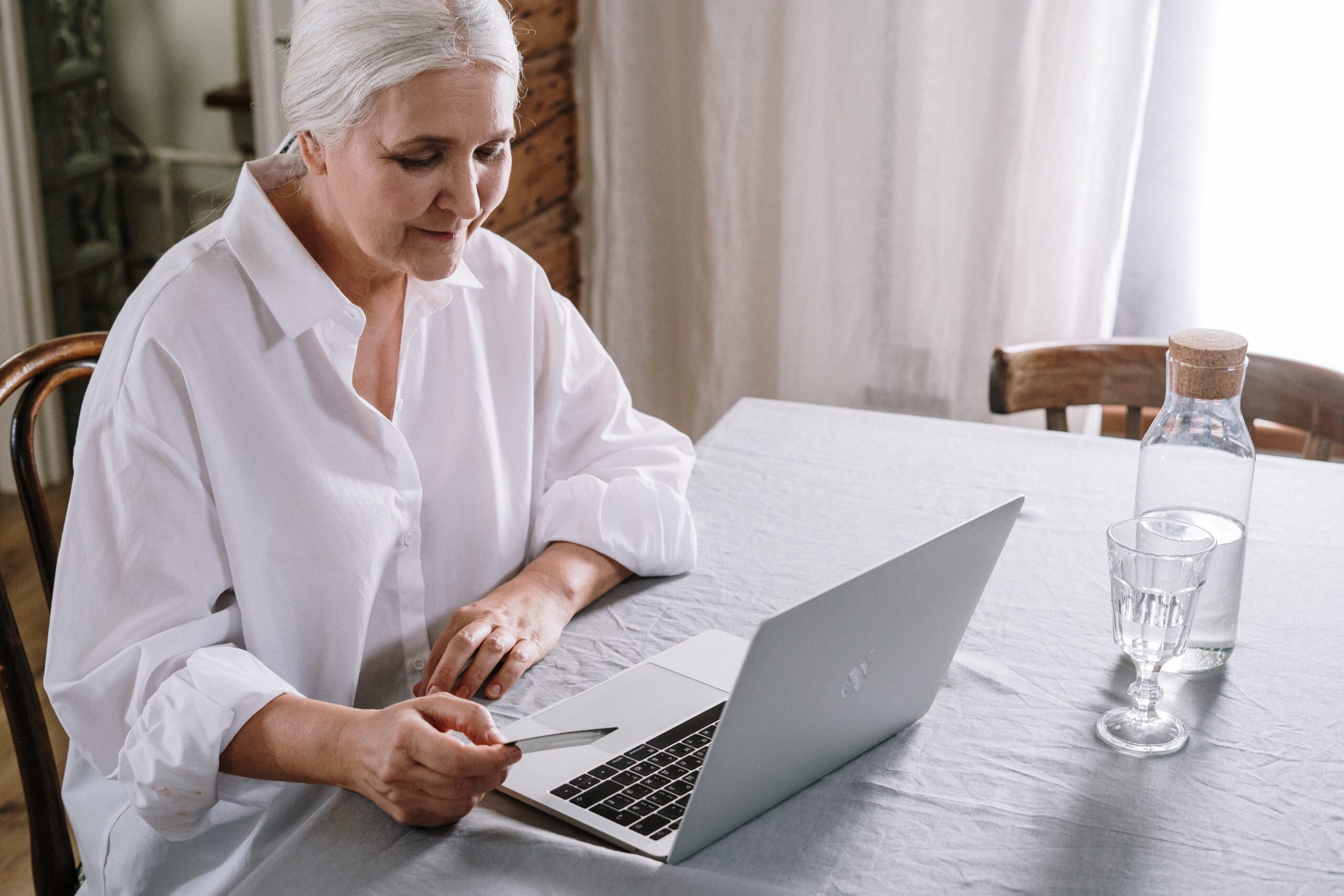 Mulher idosa compra online, mostrando a necessidade de acessibilidade digital para atingir esse público e evitar perda de vendas.