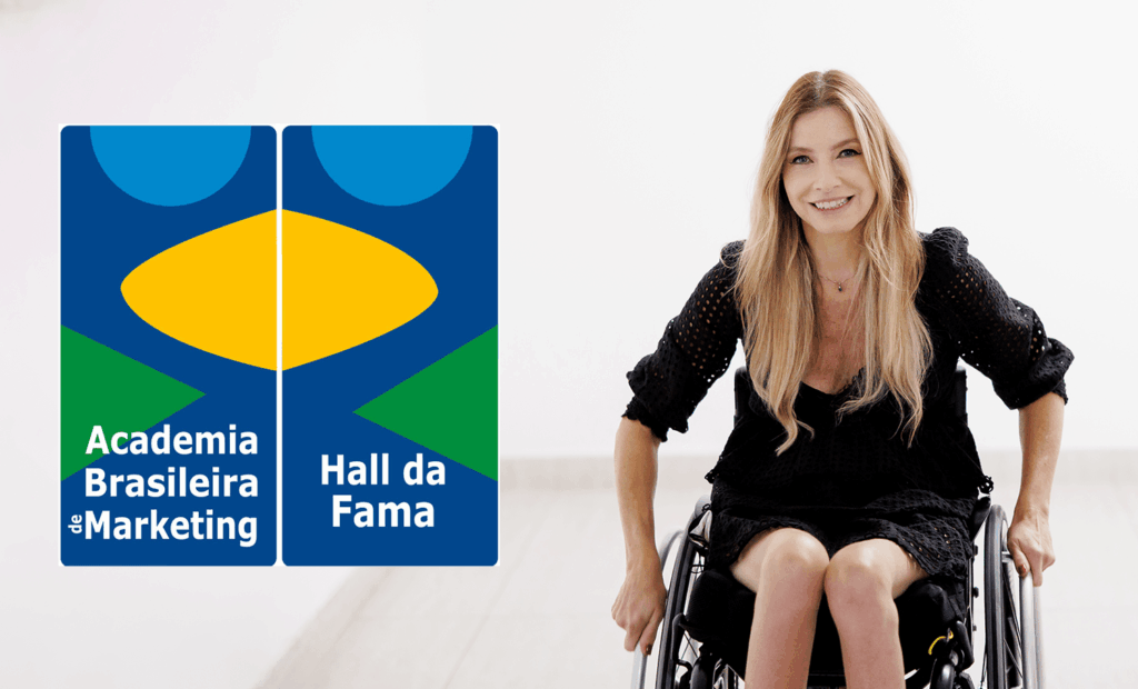 marketing. No banner ao lado esquerde temos a logo da Academia Brasileira de Marketing e do lado direito temos a foto da Andrea com um vestido preto sentada na sua cadeira de rodas.