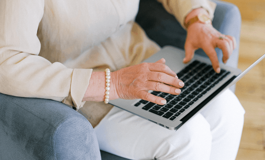 Conscientização. Imagem de uma mão idosa e feminina mexendo no notebook.