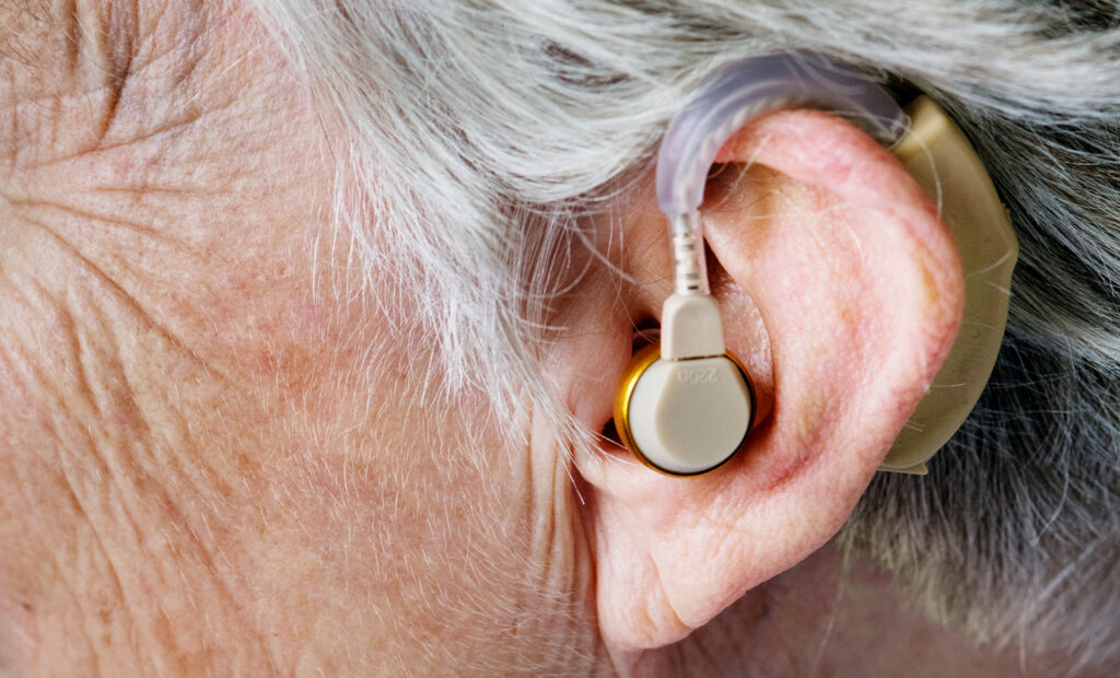 close de uma tecnologia assistiva - aparelho de audição - no ouvido de uma pessoa idosa