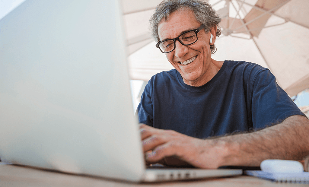 Busca. Imagem de um senhor de idade de cabelos grisalhos, sorrindo e mexendo no computador.